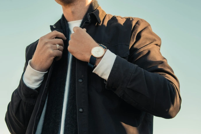 A person in a black jacket and white shirt wearing a wristwatch
